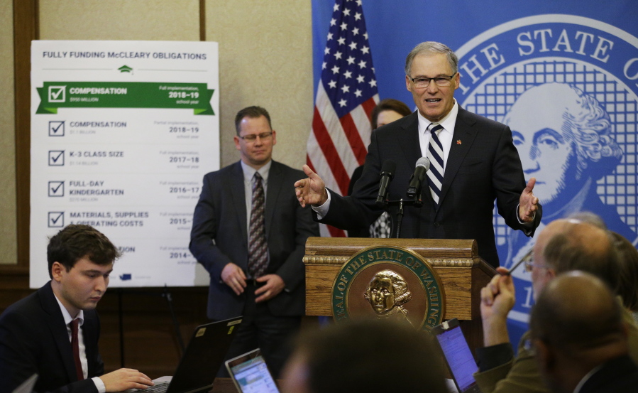 Washington Gov. Jay Inslee talks to reporters, Thursday, Dec. 14, 2017, during the unveiling of his supplemental budget proposal at the Capitol in Olympia, Wash. Inslee proposed tapping the state’s reserves to meet a final timeline required for Washington state to comply with a state Supreme Court mandate on education funding, and said he wants a new tax on carbon emissions from fossil fuels to ultimately backfill that withdrawal. (AP Photo/Ted S.