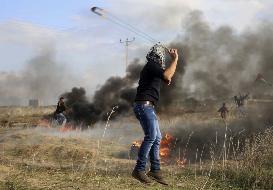 A Palestinian protester slings stones towards Israeli soldiers during clashes on the Israeli border following a protest against U.S. President Donald Trump’s decision to recognize Jerusalem as the capital of Israel, east of Gaza City, Friday, Dec. 15, 2017.