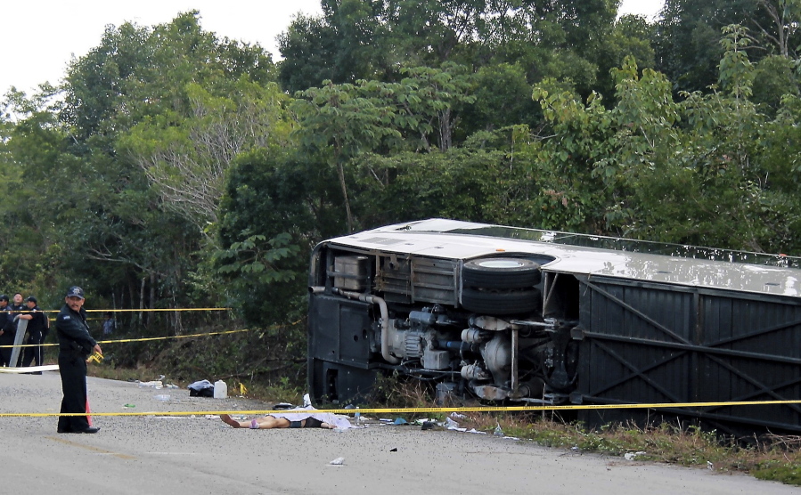 The lifeless body of a passenger lies next to an overturned bus in Mahahual, Quintana Roo state, Mexico, Tuesday, Dec. 19, 2017. The bus carrying cruise ship passengers to the Mayan ruins at Chacchoben in eastern Mexico flipped over on the highway early Tuesday.