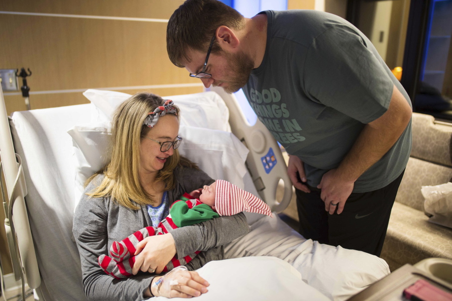 Taylor Lindeman leans in over his wife Hannah and newborn daughter, Poppy, at United Hospital in St. Paul, Minn. The Minnesota couple delivered their baby on the side of a frigid road while they were rushing to the hospital on Christmas Day.