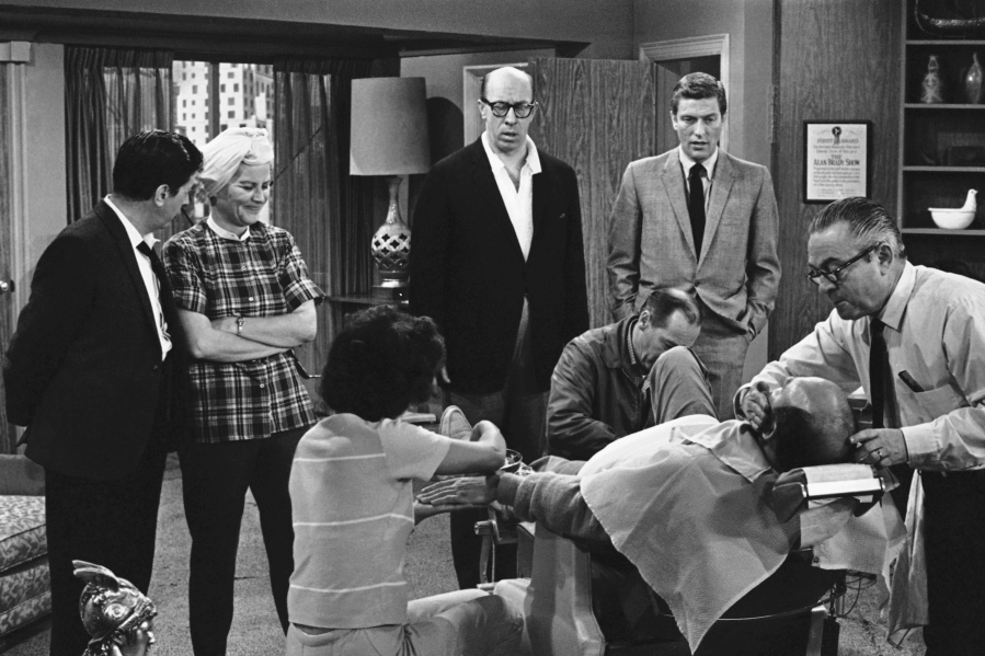 FILE- In this April 11, 1963, file photo, standing from left, Morey Amsterdam, Rose Marie, and Richard Deacon, and Dick Van Dyke, right, gather around Carl Reiner, in barber chair during a rehearsal of an episode for the "The Dick Van Dyke Show." Family spokesman Harlan Boll said Marie, the wisecracking Sally Rogers of “The Dick Van Dyke Show,” died Thursday, Dec. 28, 2017. She was 94. (AP Photo/David F.
