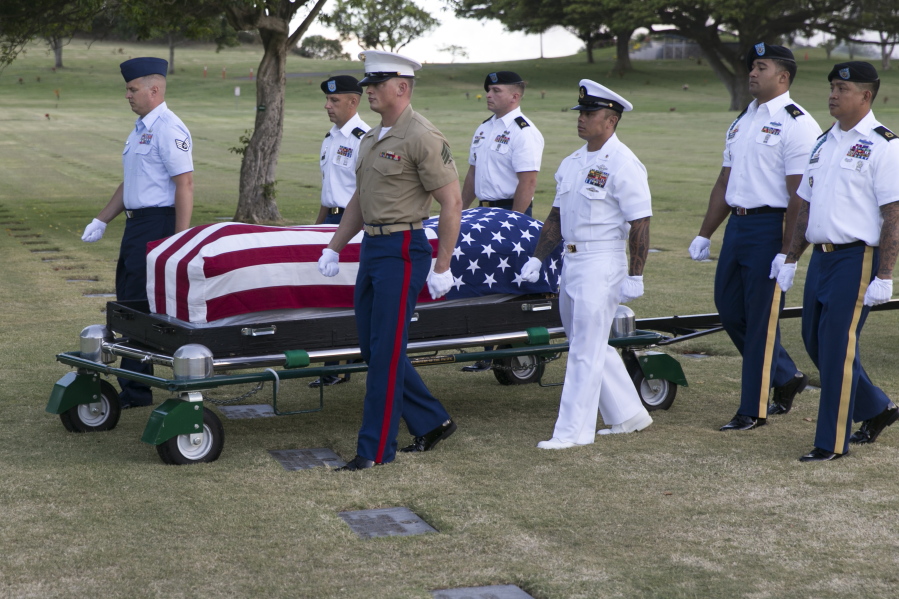 File - In this July 27, 2015 file photo, military pallbearers escort the exhumed remains of unidentified crew members of the USS Oklahoma killed in the 1941 bombing of Pearl Harbor that were disinterred from a gravesite at the National Memorial Cemetery of the Pacific in Honolulu. The military says it has identified 100 sailors and Marines killed when the USS Oklahoma capsized during the Japanese bombing of Pearl Harbor 76 years ago. The milestone comes two years after the Defense POW/MIA Accounting Agency dug up nearly 400 sets of remains from a Hawaii to identify the men who have been classified as missing since the war.