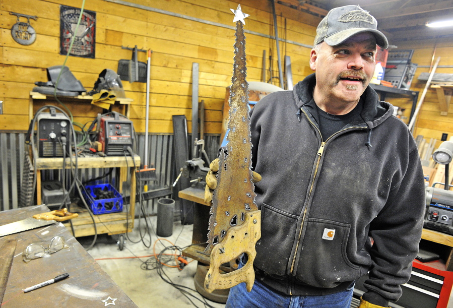 Sedro-Woolley Police Chief Lin Tucker holds a tree sculpture he made from an old handsaw at his Clear Lake shop.