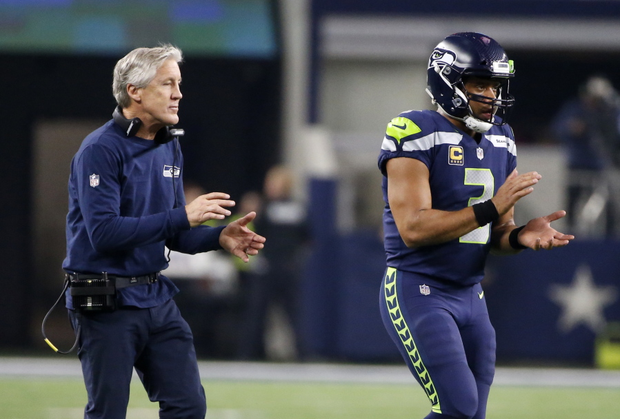 Seattle Seahawks head coach Pete Carroll and quarterback Russell Wilson walk onto the field in the second half of an NFL football game against the Dallas Cowboys on Sunday, Dec. 24, 2017, in Arlington, Texas.