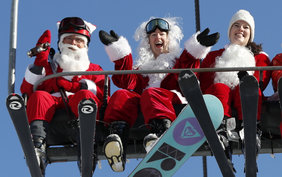 People dressed as Santa Claus ride a chairlift Sunday in Newry, Maine.