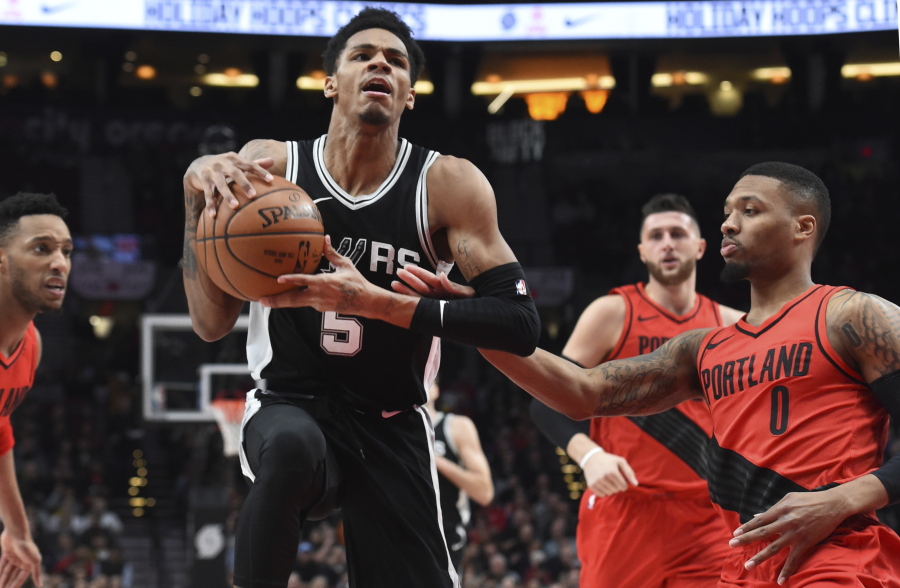San Antonio Spurs guard Dejounte Murray drives to the basket past Portland Trail Blazers guard Damian Lillard during the first half of an NBA basketball game in Portland, Ore., Wednesday, Dec. 20, 2017.