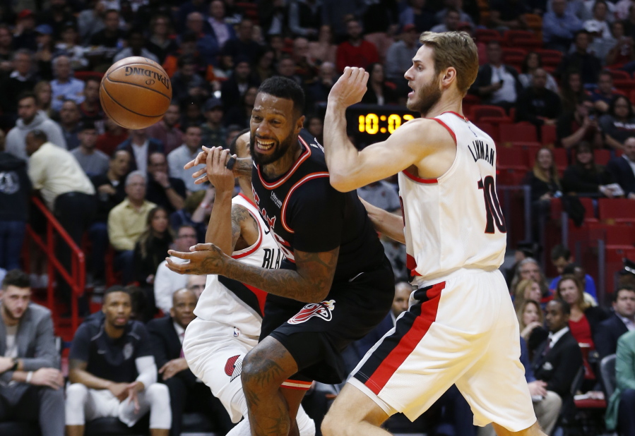 Miami Heat forward James Johnson, center, loses control of the ball as he drives against Portland Trail Blazers guard Shabazz Napier, rear, and forward Jake Layman (10) during the first half of an NBA basketball game, Wednesday, Dec. 13, 2017, in Miami.