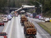 Logging trucks remain stopped just before where cars from an Amtrak train lay spilled onto Interstate 5 below alongside smashed vehicles as some train cars remain on the tracks above Monday, Dec. 18, 2017, in DuPont, Wash. The Amtrak train making the first-ever run along a faster new route hurtled off the overpass Monday near Tacoma and spilled some of its cars onto the highway below, killing some people, authorities said. Seventy-eight passengers and five crew members were aboard when the train moving at more than 80 mph derailed about 40 miles south of Seattle before 8 a.m., Amtrak said.