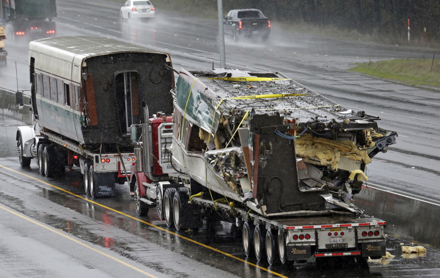 Two damaged train cars sit on flatbed trailers Tuesday after being taken from the scene of an Amtrak train crash onto Interstate 5 a day earlier in DuPont.