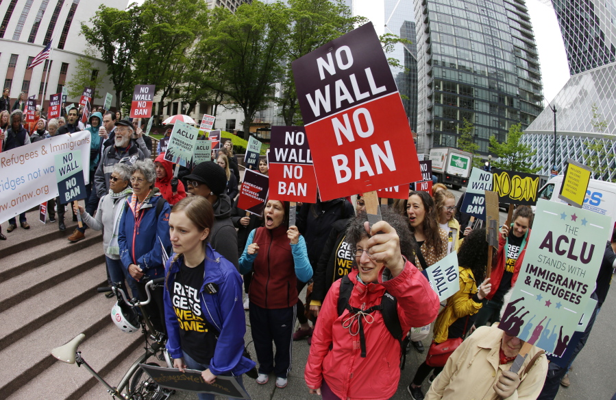 FILE - In this May 15, 2017, file photo, protesters wave signs and chant during a demonstration against President Donald Trump’s revised travel ban outside a federal courthouse in Seattle. The U.S. Supreme Court’s decision allowing Trump’s third travel ban to take effect, at least for now, has intensified the attention on a legal showdown before three judges in Seattle who have previously been cool to the administration’s efforts. Ninth U.S. Circuit Court of Appeals Judges Ronald Gould, Richard Paez and Michael Hawkins are scheduled to hear arguments Wednesday afternoon, Dec. 6, 2017 in Hawaii’s challenge to the latest version of the travel ban. (AP Photo/Ted S.
