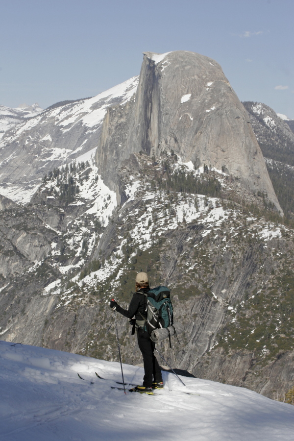 This undated image provided by Yosemite Hospitality shows a cross-country skier in Yosemite National Park in California in winter with the famous Half Dome formation in the background. The park offers solitude, scenery and activities like skiing and snowshoeing in the offseason when there are fewer crowds.