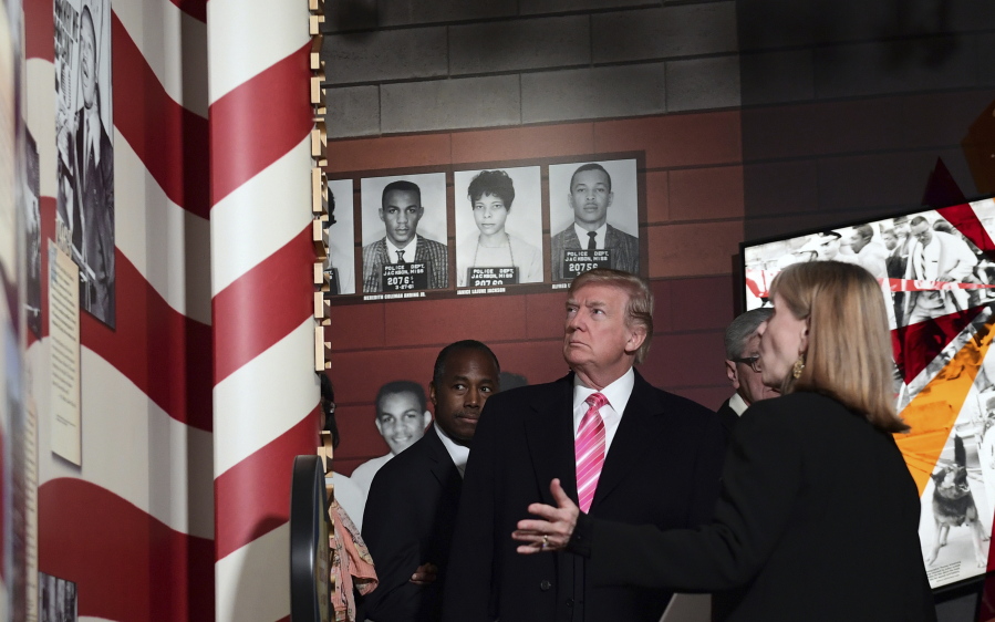 President Donald Trump, center, listens to Museum Division Director Lucy Allen, right, during a tour of the newly opened Mississippi Civil Rights Museum in Jackson, Miss., Saturday, Dec. 9, 2017. Housing and Urban Development Secretary Ben Carson, left, joins the president on the tour.