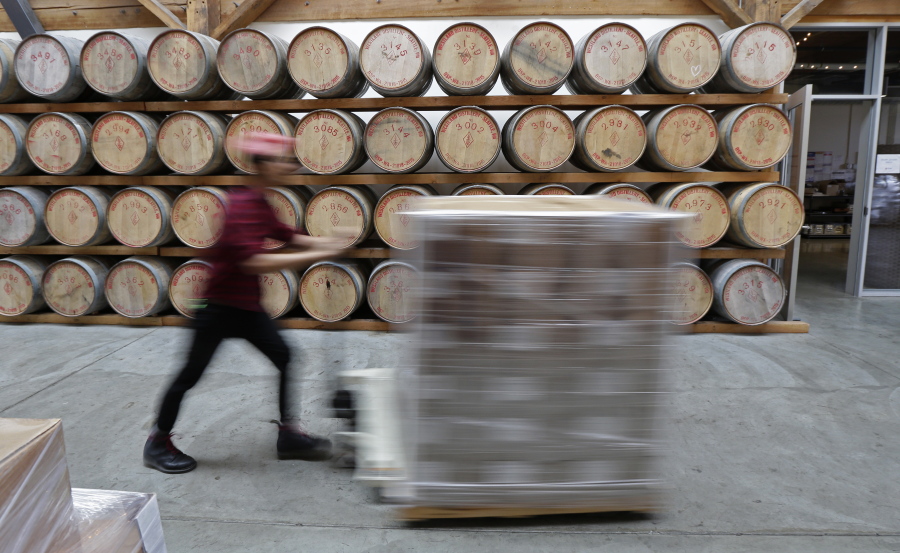 In this Nov. 14, 2017 photo, Nathan Bazan moves a pallet of supplies past whiskey aging in oak barrels at the Westland Distillery in Seattle. Westland is taking an unusual step for America's booming spirits industry: making a whiskey using smoke from peat grown locally in Washington state. (AP Photo/Ted S.
