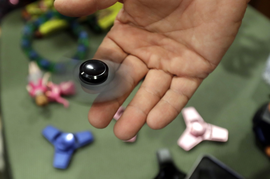 FILE - In this Thursday, May 11, 2017, file photo, Funky Monkey Toys store owner Tom Jones plays with a fidget spinner in Oxford, Mich. Fidget spinners were among the most searched topics on Google in 2017.
