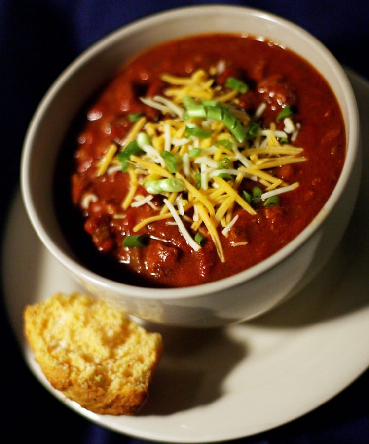 Chili garnished with cheese and scallions and served with a side of cornbread is perfect for a cold winter night.