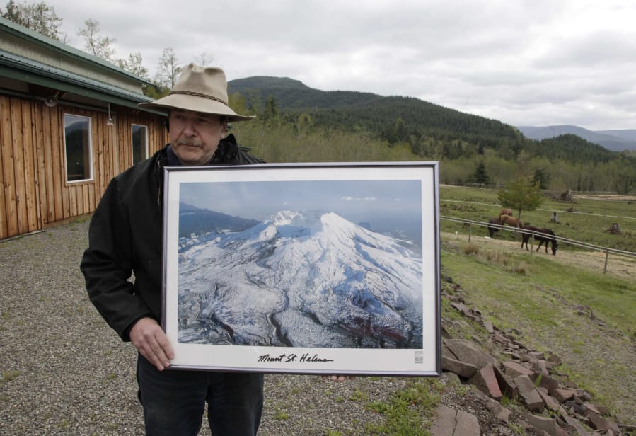 Mark Smith, owner of the Eco Park Resort at Mount St. Helens, holds a photo of the volcano as he stands on his property in Washington on April 22, 2010.