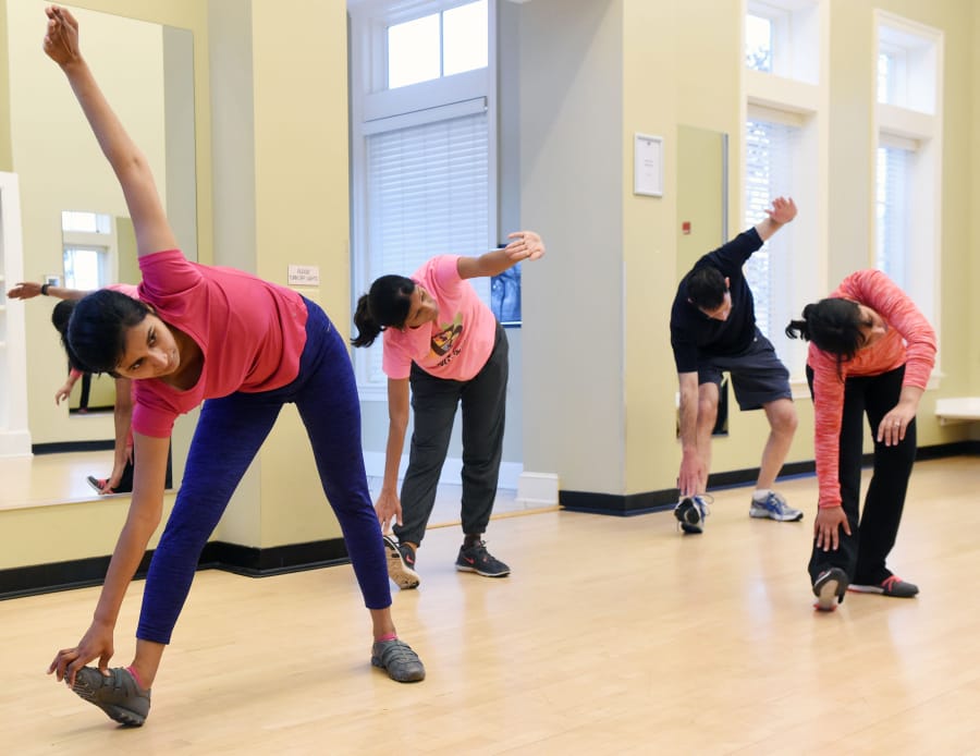 From left, Swati Reddy, Elkridge, Joyce Mahabier, Ellicott City, Alan Rodin, Fulton, and Navya Pondicherry, Burtonsville, warm down during their Bend It Like Bollywood class on Dec. 9, 2017 at the Maple Lawn Community Center. The fitness-oriented class uses Bollywood music and dance movements.