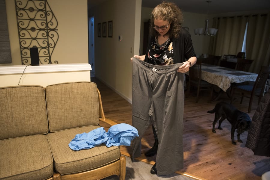 Meghan Green of Ridgefield holds up an old pair of size 36 pants in her home on Tuesday. Green recently bought her first pair of size 14 jeans. After years of dreading clothes shopping, it’s now something she can look forward to.