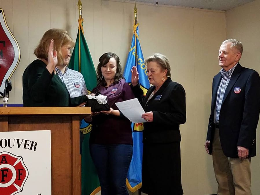 Anne McEnerny-Ogle, left, takes the oath of office Monday at the Vancouver Firefighters Union Hall. State Supreme Court Justice Susan Owens, second from right, performed the ceremony. The new mayor was surrounded by her son John Ogle (partially obscured), his girlfriend Kylie Silvester and the mayor’s husband, Terry Ogle, right.