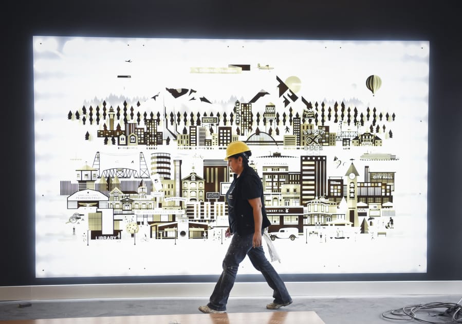 Angeles Lopez walks past artwork detailing Portland and Vancouver while preparing to paint in the lobby of The Uptown apartments on Wednesday. The complex is expected to open fully by the end of the month.
