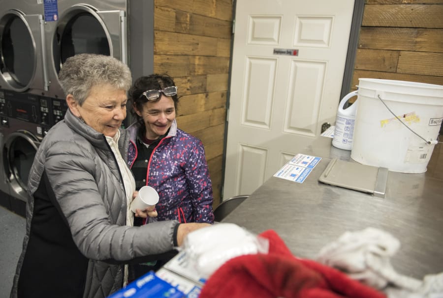 Volunteer Bert Day of Vancouver helps Deana Lentz, homeless in Vancouver, start up a loaded washer during the free laundry night at Laundry Love on Thursday evening, Jan. 4, 2018. The laundromat opened this winter after undergoing repairs from an accident in May.