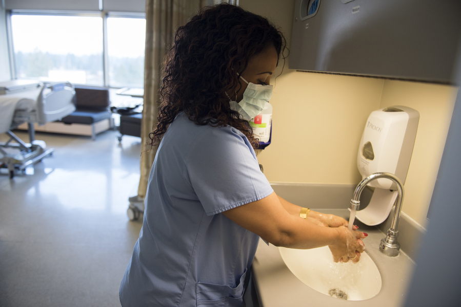 Certified nursing assistant Meron Mesfin washes her hands before entering the rooms of influenza patients on Tuesday afternoon at PeaceHealth Southwest Medical Center in Vancouver. The hospital has additional precautionary measures in place — such as masks and extra handwashing — to prevent the spread of influenza.