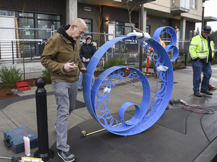 Builder Dave Frei, left, and designer Jennifer Corio, the husband-and-wife team known as Colbalt Designworks, consider the placement of their metal sculpture “Bubbles” on the Washington Street sidewalk outside The Uptown Apartments, which is shortly to open to tenants.
