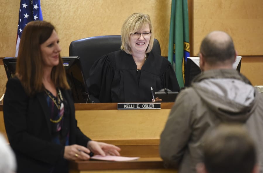 Defense attorney Lisa Toth, left, listens as Judge Kelli E. Osler, center, chats with a Mental Health Court participant Wednesday during a compliance review in Clark County District Court.