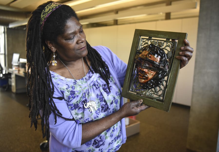 Artist Claudia Carter, who’s curated an exhibit at the Vancouver Community Library about “The History and Art of African-Americans in the Northwest” for the local NAACP, discusses her original ceramic piece called “Enslaved.” (Ariane Kunze/The Columbian)