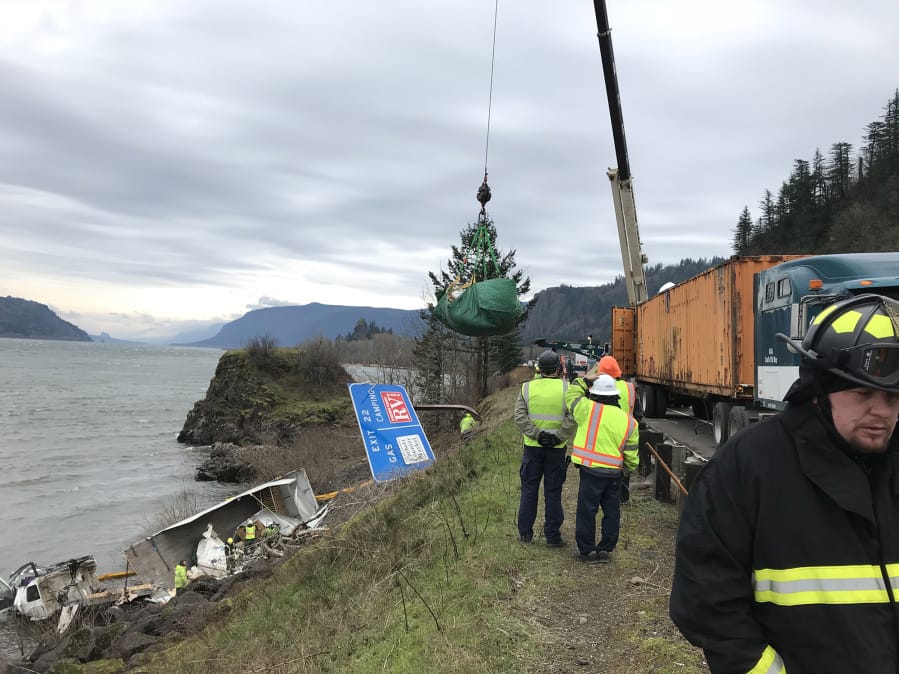 Crews, including TLC Towing of Ridgefield, work Wednesday to clean up after a tractor-trailer crashed into a disabled car and rolled off Interstate 84 in Oregon into the Columbia River on Monday.