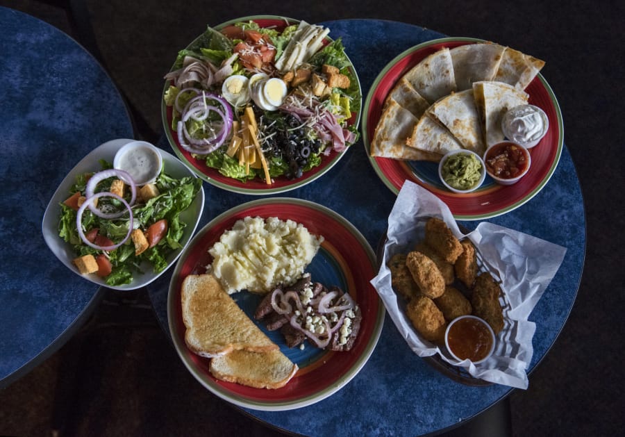The Chef’s Salad, clockwise from top left, the chicken quesadilla, red stuffed jalapeño poppers and the steak strip dinner with a side salad are among the selections available at Out-A-Bounds Sports Bar & Grill in Vancouver.