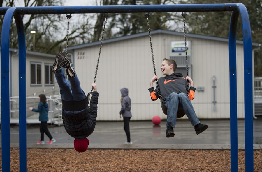 La Center Elementary School fifth-graders Carter Sherry, 10, left, and Jackson Simmonds, 11, catch a ride on the swings during recess near two of the nine portable classrooms at K-8 campus in 2018.