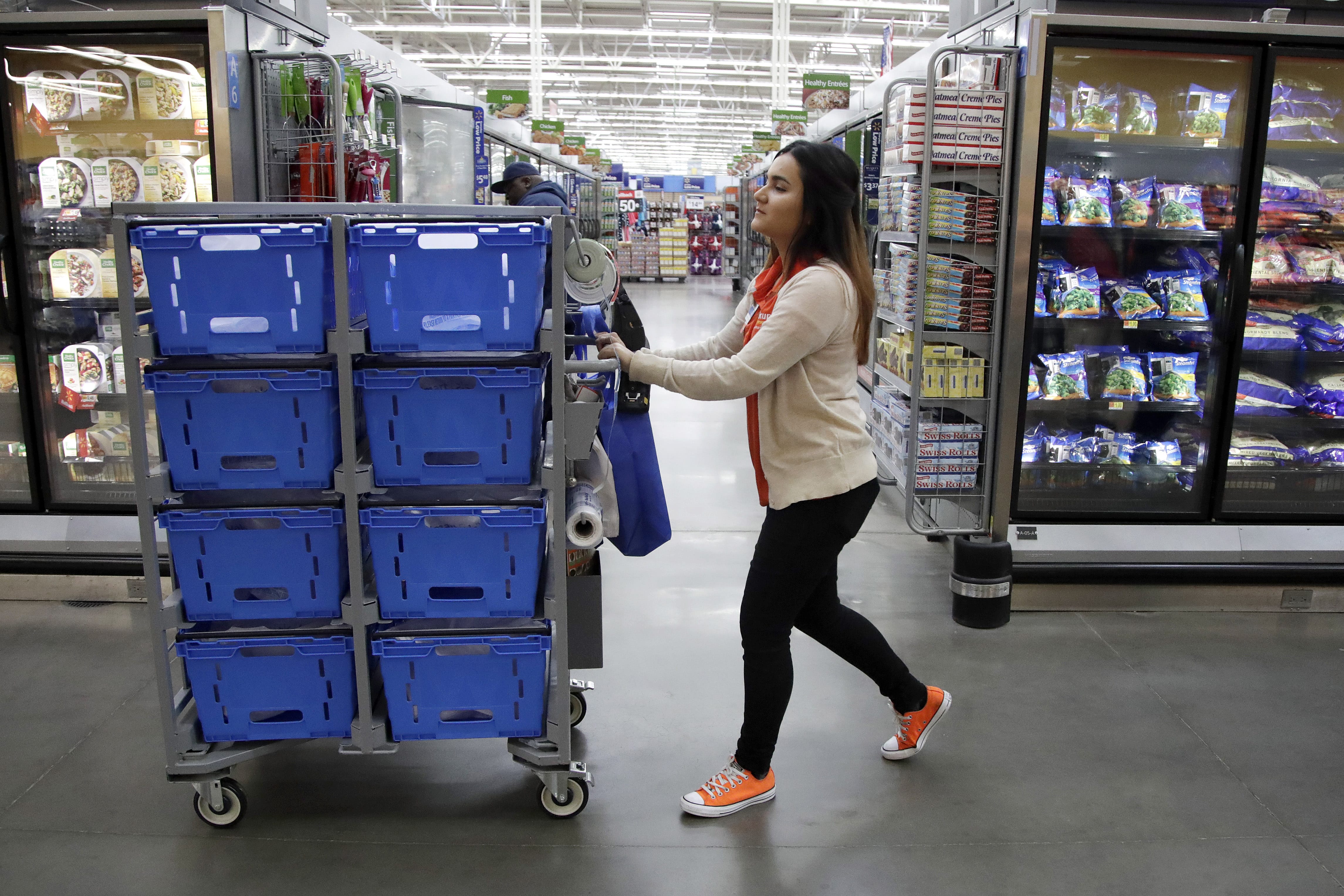 In this Thursday, Nov. 9, 2017, photo, Laila Ummelaila, a personal shopper at the Walmart store in Old Bridge, N.J., pushes a cart with bins as she shops for online shoppers. On Thursday, Jan. 11, 2018, Walmart announced it is boosting its starting salary for U.S. workers to $11 an hour, giving a one-time $1,000 cash bonus to eligible employees and expanding its maternity and parental leave benefits.