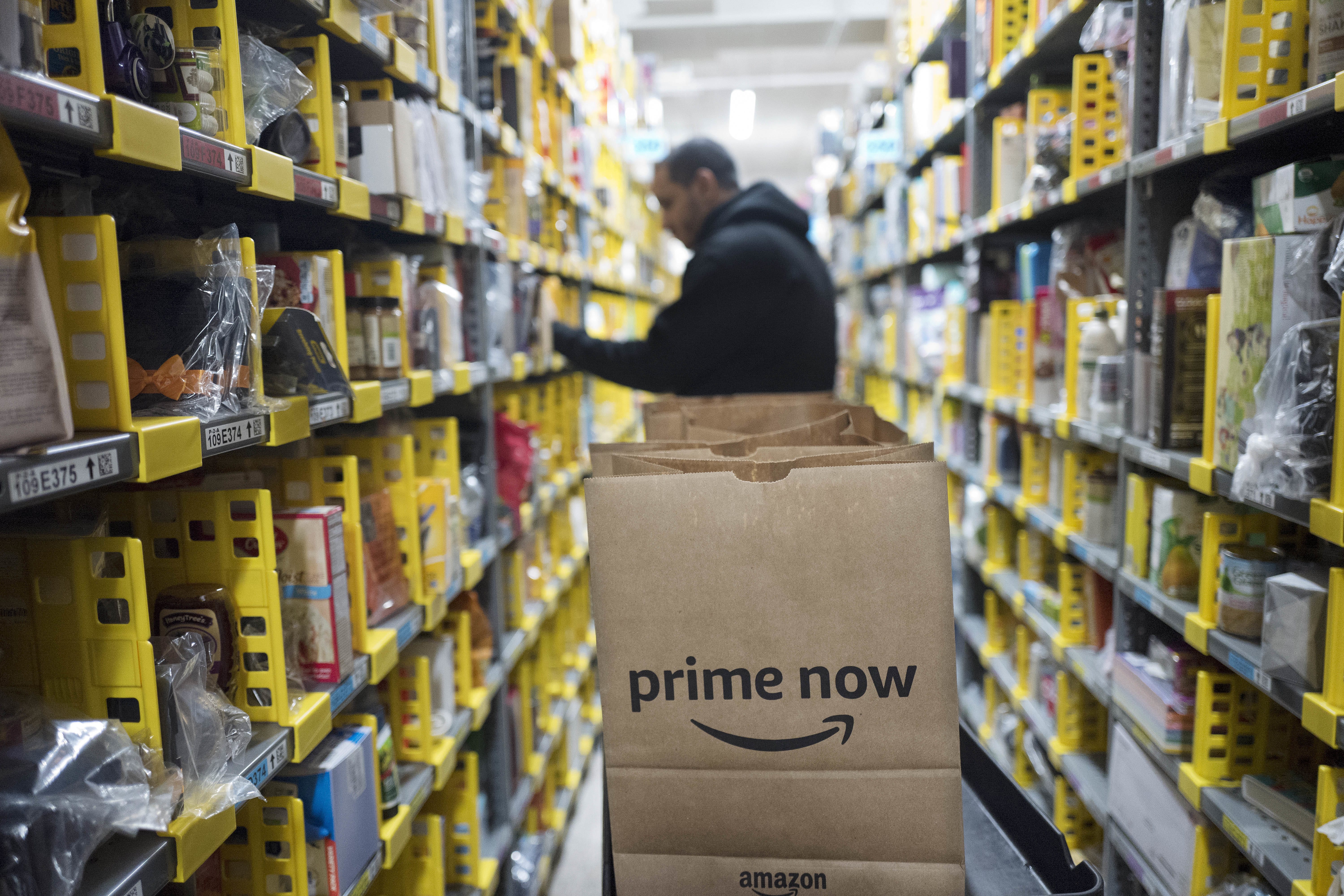 FILE - In this Wednesday, Dec. 20, 2017, file photo, a clerk reaches to a shelf to pick an item for a customer order at the Amazon Prime warehouse, in New York. Amazon announced Thursday, Jan. 18, 2018, that it has narrowed down its potential site for a second headquarters in North America to 20 metropolitan areas, mainly on the East Coast.