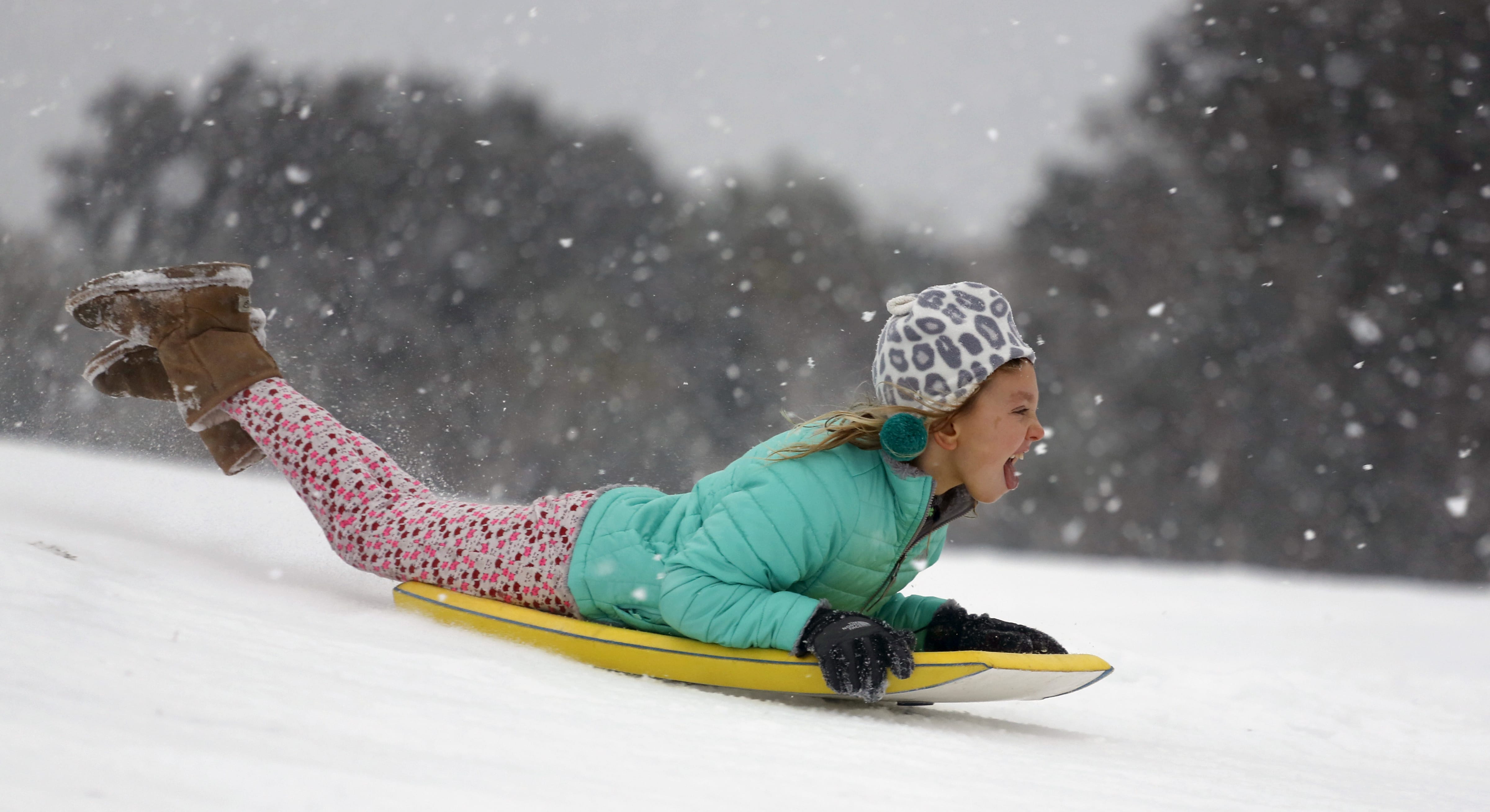Finley Bork, 7, uses a boogie board, typically used on the beach, for sledding down a hill on a golf course at the Isle of Palms, S.C., Wednesday, Jan. 3, 2018.  A brutal winter storm smacked the coastal Southeast with a rare blast of snow and ice Wednesday, hitting parts of Florida, Georgia and South Carolina with their heaviest snowfall in nearly three decades.