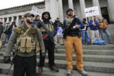 Ian Stobie, left, Jake Garza, second from left, and Ben Garrison, third from left, and all of Puyallup, open-carry their guns on the steps of the Legislative Building as they attend a gun rights rally, Friday, Jan. 12, 2018, at the Capitol in Olympia, Wash. A Washington state Legislature Senate committee held a public hearing Monday, Jan. 15, on several bills related to guns, including measures to prohibit high-capacity magazines and to ban so-called bump stocks, trigger modification devices designed to increase the rate of fire of a firearm. (AP Photo/Ted S.