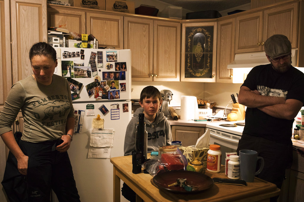Brennan Caton, center, Misty Lawson and Courtney Caton, right, listen to the coast guard radio inside their home for updates on the tsunami warnings that shook Tofino, British Columbia, after the Alaskan earthquake on Tuesday, Jan. 23, 2018. A tsunami warning issued for coastal British Columbia was canceled Tuesday morning after some people living along parts of the province's coast evacuated to higher ground when a powerful earthquake struck off Alaska.