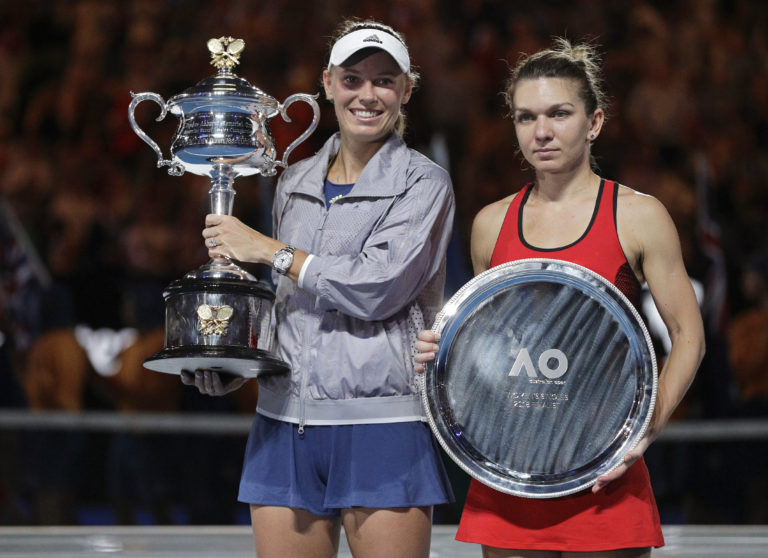 Denmark's Caroline Wozniacki, left, holds her trophy after defeating Romania's Simona Halep, right, in the women's singles final at the Australian Open tennis championships in Melbourne, Australia, Saturday, Jan. 27, 2018.