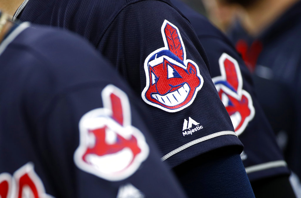 Members of the Cleveland Indians wear uniforms featuring mascot Chief Wahoo as they stand on the field for the national anthem before a baseball game against the Baltimore Orioles in Baltimore. The Cleveland Indians are taking the divisive Chief Wahoo logo off their jerseys and caps, starting in 2019.