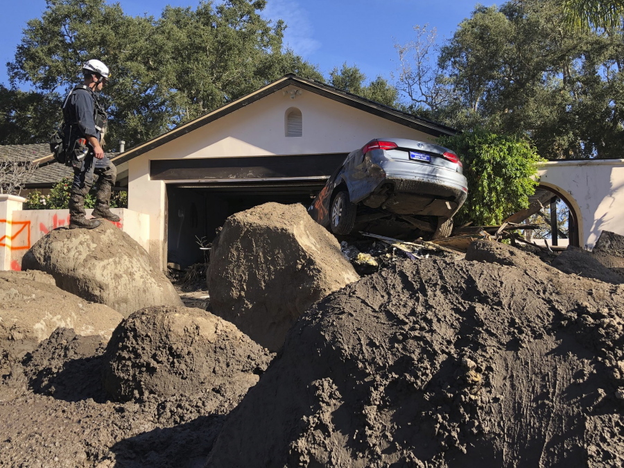 Capt. John Pepper, Fresno Fire Department, and Rescue Squad Leader RTF-5 searches homes Saturday off East Valley Road in Montecito, Calif.