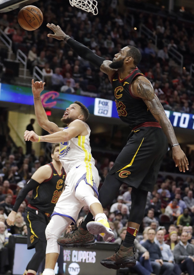 Cleveland Cavaliers’ LeBron James blocks a shot by Golden State Warriors’ Stephen Curry, left, in the second half of an NBA basketball game, Monday, Jan. 15, 2018, in Cleveland.