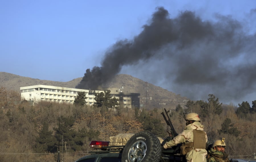 Afghan security personnel stand guard as black smoke rises from the Intercontinental Hotel after an attack, in Kabul, Afghanistan. The Islamic State group and the Taliban are competing to take credit for a horrific spike in violence in Afghanistan over the last month, and analysts say both insurgent groups are growing in strength as security forces wither under their relentless attacks and a feuding government struggles to win over citizens.