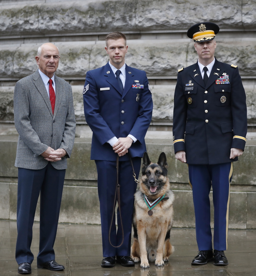 John Wren, left, with Military dog Ayron and his handler Staff Sergeant Jeremy Mayerhoffer, centre, and US Lieutenant Colonel Alan Throop, right, during a ceremony to posthumously award the PDSA Dickin Medal, , to Chips, in London, Monday.