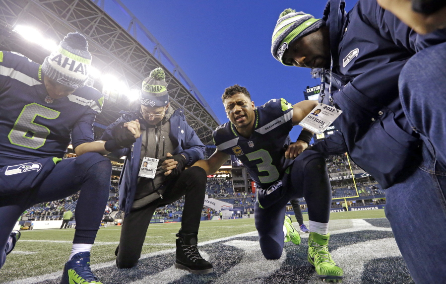 Seattle Seahawks quarterback Russell Wilson (3) prays with Austin Davis (6) and Pastor Judah Smith, second from left, after the team lost to the Arizona Cardinals in an NFL football game, Sunday, Dec. 31, 2017, in Seattle.