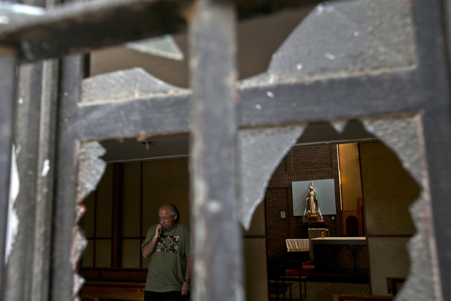 A church employee surveys the damage caused by a fire bomb Friday at Emmanuel Catholic Church in Santiago, Chile. Three churches were attacked overnight, with leaflets against the visit of Pope Francis dropped at the scene. Nobody was injured or arrested.