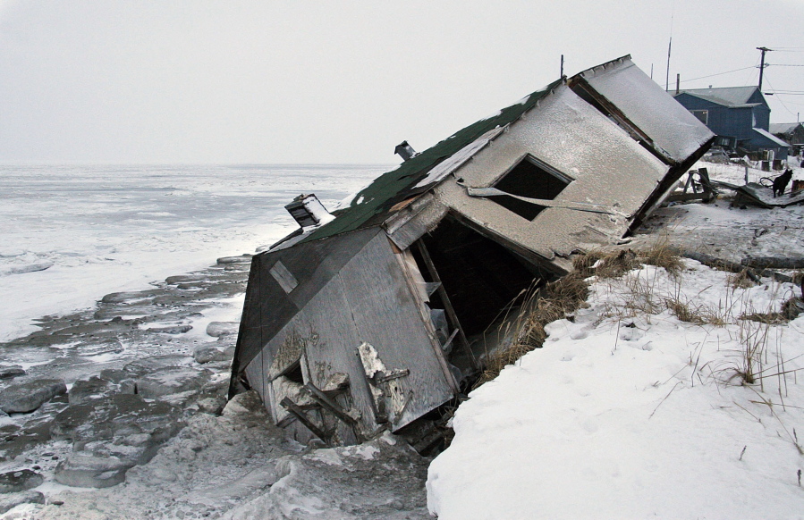 FILE - In this Dec. 8, 2006, file photo, Nathan Weyiouanna’s abandoned house at the west end of Shishmaref, Alaska, sits on the beach after sliding off during a fall storm in 2005. Alaska health officials are warning that serious health issues could crop up as the state warms. A report by the Alaska Division of Public Health released this week says longer growing seasons and fewer deaths from exposure are likely positive outcomes from climate change. But the 77-page report says additional diseases, lower air quality from more wildfires, melting permafrost and disturbances to local food sources also are potential outcomes. Warming already has thawed soil and eroded coastlines, leading at least three villages, Shishmaref, Kivalina and Newtok to consider relocating.