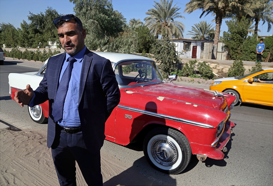 In this Friday, Jan. 12, 2018 photo, Nashwan Shakir Mahmoud stands with his his red and white 1955 Chevrolet coupe that survived three years of war and upheaval, in Baghdad, Iraq. The promise of better days after Iraq’s victory against the Islamic State group is rekindling interest in vintage cars.