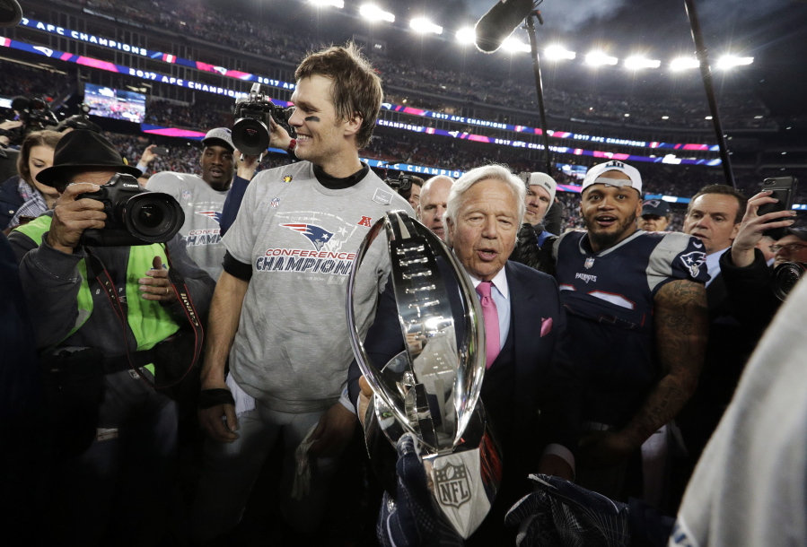 New England Patriots owner Robert Kraft, center, carries the trophy between quarterback Tom Brady, left, and safety Patrick Chung as they leave the field after the AFC championship NFL football game against the Jacksonville Jaguars, Sunday, Jan. 21, 2018, in Foxborough, Mass. The Patriots won 24-20. (AP Photo/David J.