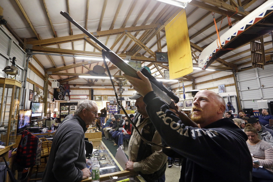 Customer Andy Muscato looks over a rifle on Oct. 20, 2017, before an auction at Johnny’s Auction House, where the company handles gun sales for several police departments and the Lewis County Sheriff’s Office, in Rochester, Wash.