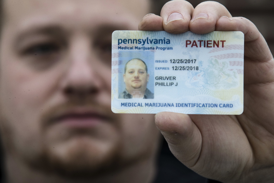 Phil Gruver shows his Pennsylvania medical marijuana card in Emmaus, Pa. Pennsylvania authorities are warning patients that federal law bars marijuana users from having guns or ammunition. Gruver is weighing what to do with his .22-caliber rifle and handgun.